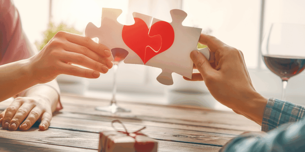 Two people holding puzzle pieces together making a heart