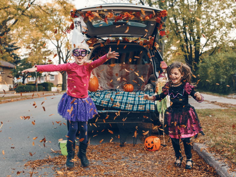 Kids dressed up for halloween throwing leaves