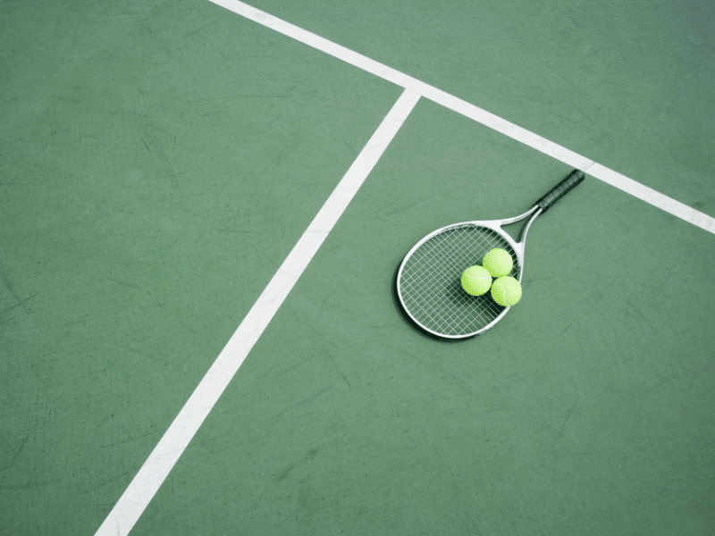 tennis racket with balls on court