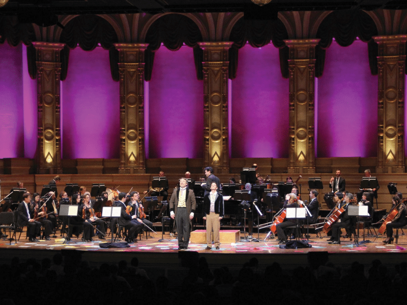 men standing in front of orchestra on stage